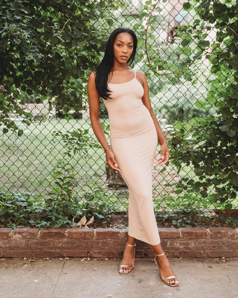 Nude color, figure hugging, long dress has thin adjustable sling and scoop neck. 