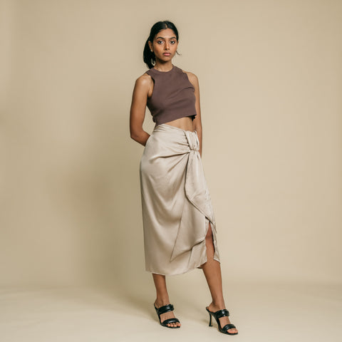 Beige, under knee skirt has front slit and stylish knot detail on waist.