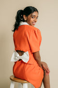 V-neck, button up jacket dress featuring cutaway back with white big ribbon.   